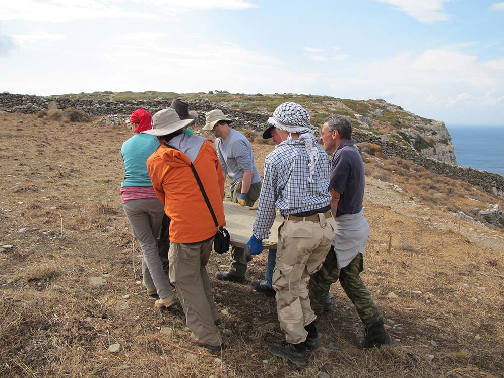 Six people carrying a schist slab that will be used as a table top