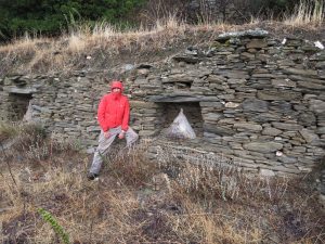 Paul Donnelly, in front of a stone wall containing beehives