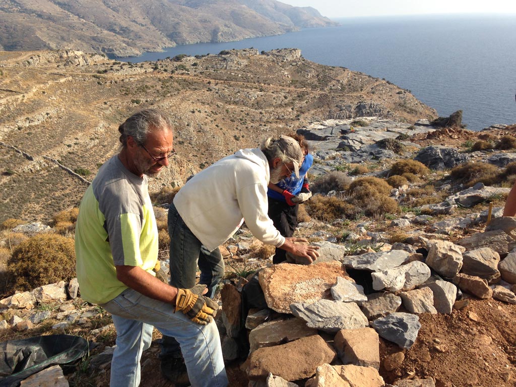 Steve Vasilakis and Kostis Fragiadakis place stones on a protective wall they are building around a trench