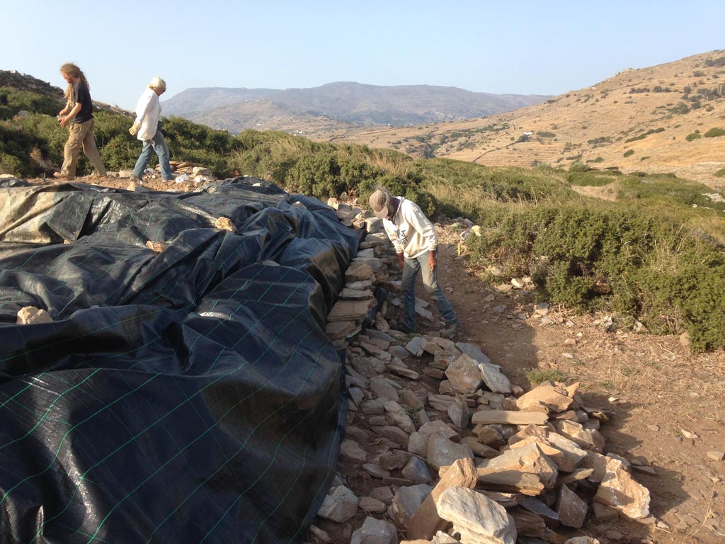Callum Ferrell, Meg Miller and Kostis Fragiadakis select and place stones onto the geo-textile to protect the trench