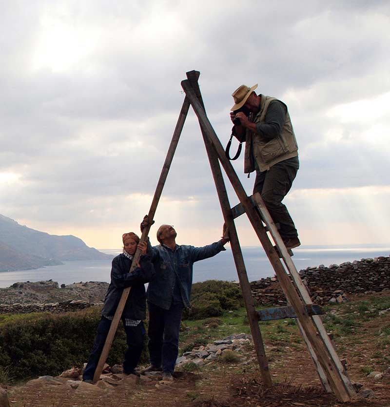 Bob Miller taking a photograph from an improvised ladder which is supported by Kristen Mann and Steve Vasilakis