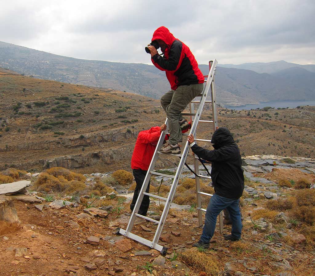 Bob Miller taking a photograph from a ladder at Zagora. The ladder is supported by Paul Donnelly and Anne Hooton